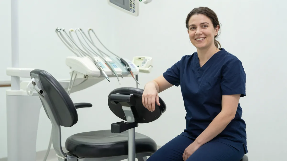 Dental assistant using a saddle stool with armrests during clinical work