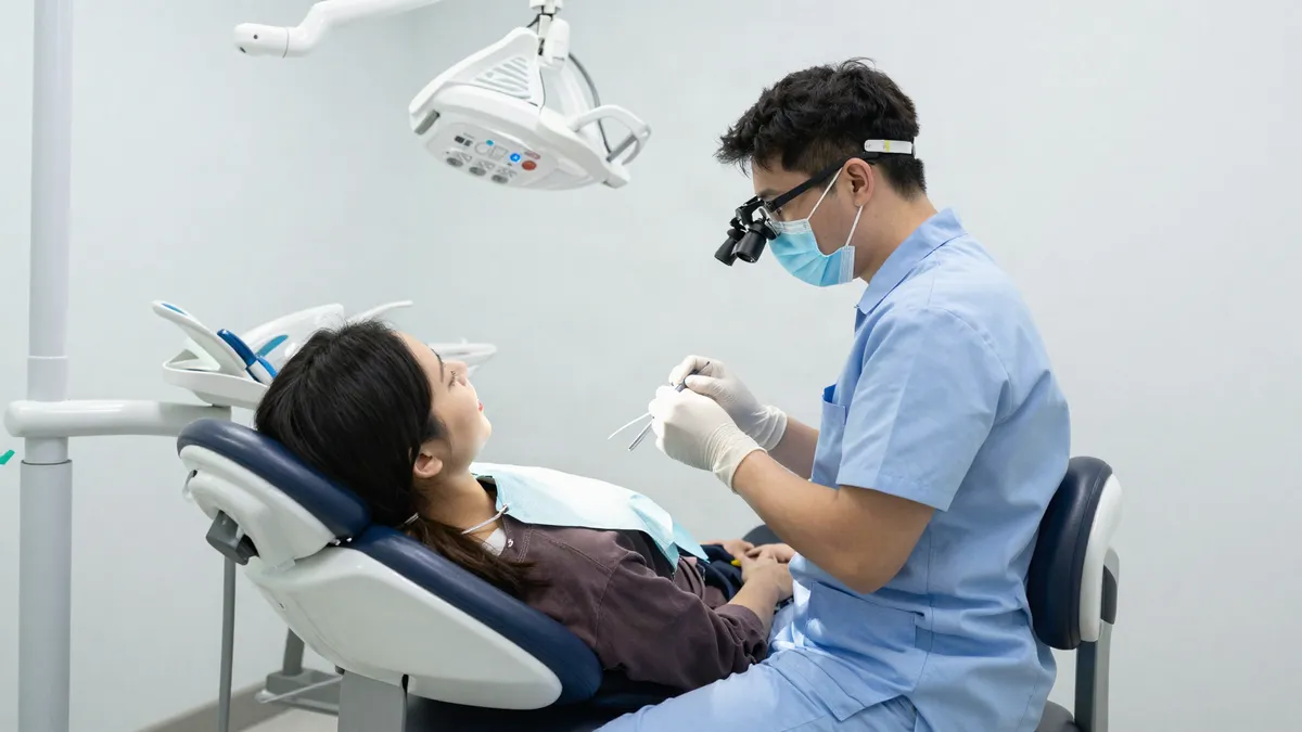 Clinician wearing dental loupes while treating a patient in an upright posture